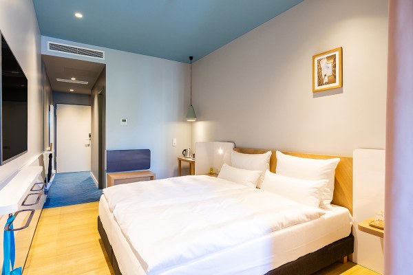 Aufnahme eines kleinen gemütlichen Hotelzimmers mit blauen Akzenten