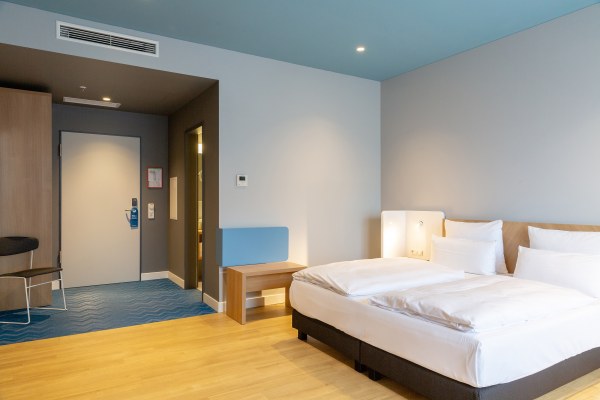 Aufnahme im modernen Hotelzimmer mit Blick auf das Bett und den Eingangsbreich